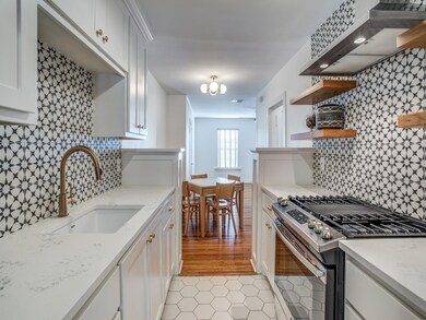Kitchen featuring white cabinetry, wall chimney ex