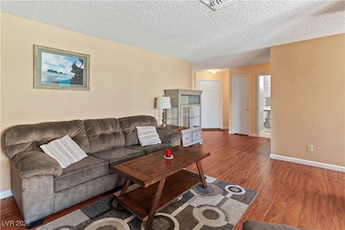 Living room featuring wood finished floors, a textured ceiling, and baseboards