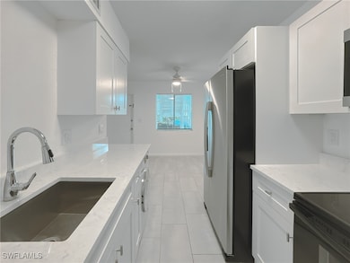 Kitchen featuring white cabinets, stainless steel fridge, and light stone counters