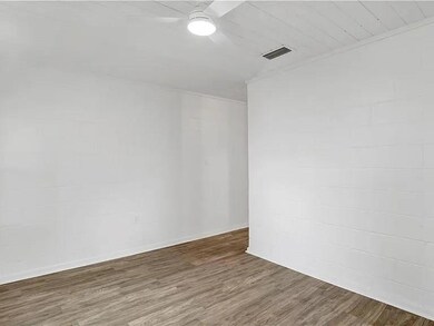 Spare room featuring wood finished floors, ceiling fan, and concrete block wall