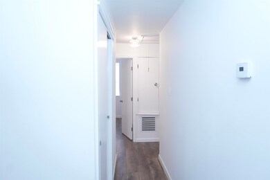 Corridor with dark wood-type flooring and baseboards