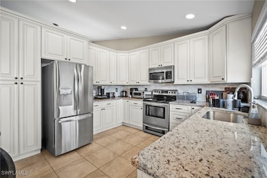 Kitchen with appliances with stainless steel finishes, light stone countertops, white cabinetry, and recessed lighting