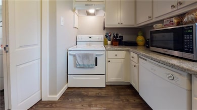 Kitchen featuring white appliances, dark wood fini