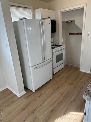 Kitchen featuring white cabinetry, range, freestanding refrigerator, light wood-style flooring, and light countertops