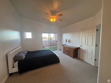 Bedroom featuring light colored carpet, vaulted ceiling, access to exterior, and ceiling fan