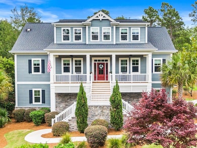 View of front of home with stairway, covered porch, stone siding, ceiling fan, and a shingled roof
