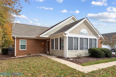Single story home with a sunroom, a front yard, brick siding, and a shingled roof