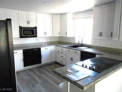 Kitchen with black appliances, a sink, white cabin