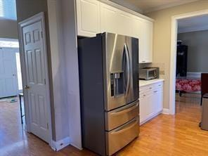 Kitchen featuring white cabinetry, baseboards, sta