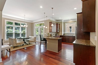 Kitchen featuring a peninsula, backsplash, dark wood-style floors, a kitchen breakfast bar, and dark stone countertops