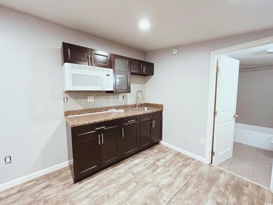 Kitchen with white microwave, backsplash, dark bro