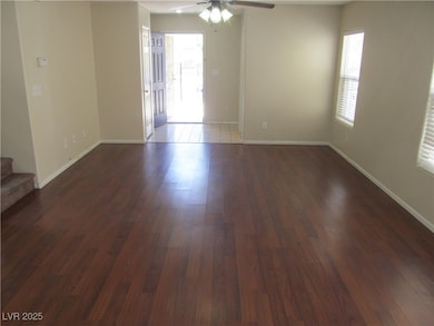 Spare room with ceiling fan, stairs, dark wood-sty