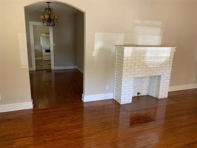 Unfurnished living room with wood-type flooring, a chandelier, baseboards, and arched walkways