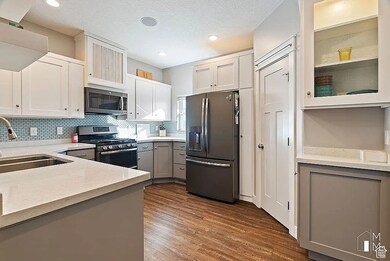 Kitchen featuring gray cabinetry, appliances with stainless steel finishes, backsplash, glass insert cabinets, and a textured ceiling