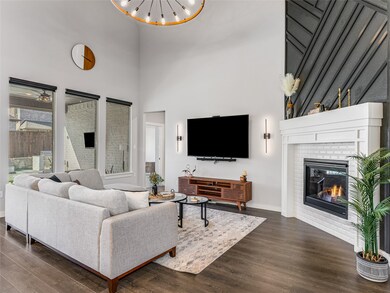 Living room with dark wood-style flooring, a high ceiling, a brick fireplace, and a chandelier