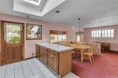 Kitchen with brown cabinets, a peninsula, tile countertops, light tile patterned floors, and recessed lighting