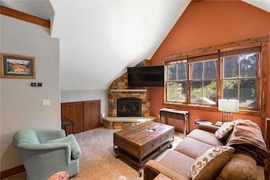 Carpeted living room featuring a stone fireplace a