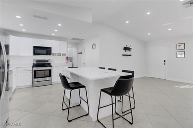 Kitchen with light tile patterned floors, a breakfast bar area, a center island, white cabinets, and stainless steel range with electric cooktop