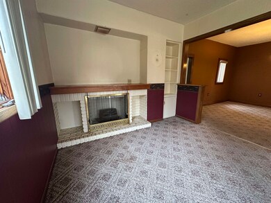 Unfurnished living room with carpet floors and a brick fireplace