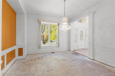 Foyer featuring a decorative wall, ornamental molding, a chandelier, and a wainscoted wall