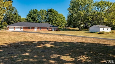 View of grassy yard featuring a garage and an outbuilding
