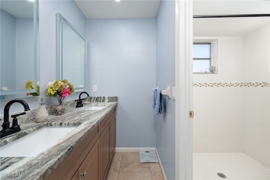 Bathroom featuring tiled shower and vanity