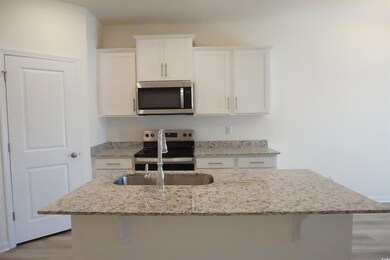 Kitchen with white cabinets, sink, light stone cou