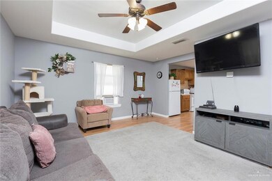 Living room featuring light hardwood / wood-style flooring, a tray ceiling, cooling unit, and ceiling fan