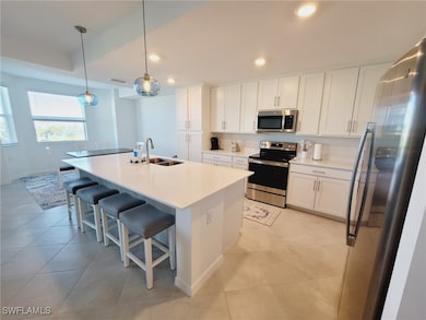 Kitchen with white cabinets, pendant lighting, sta