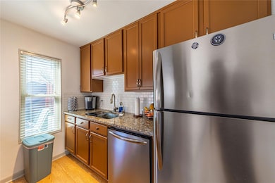 Kitchen featuring dark stone counters, a sink, sta