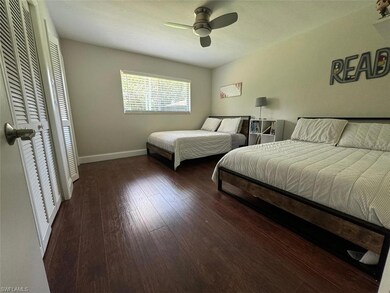 Spacious bedroom with wood-style floors, ceiling fan, and ample natural light — can comfortably accommodate two beds.
