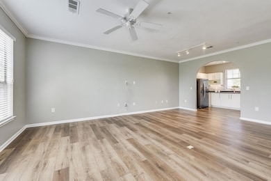 Unfurnished living room with crown molding, arche