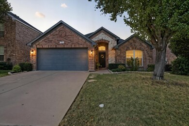 French country inspired facade featuring a front yard, concrete driveway, an attached garage, stone siding, and brick siding