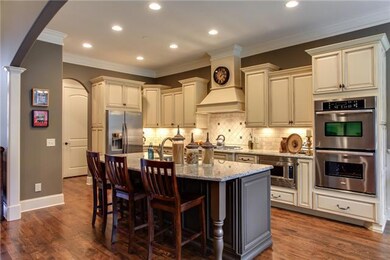 A WOW Kitchen with GORGEOUS custom painted/glazed furniture grade cabinetry, Upscale Granite Countertops, and a Tiled Backsplash with accents make this room pop!   You'll entertain many a crowd with the large center island located next to the Den.