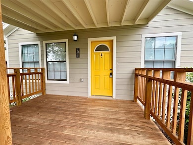 Adorable covered front porch/patio with cheery yellow door to relax on