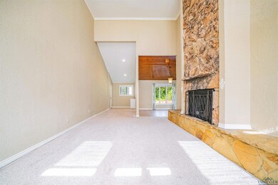 Unfurnished living room with a stone fireplace, carpet flooring, ornamental molding, and baseboards