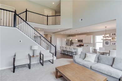 Living area featuring a chandelier, stairs, a towering ceiling, recessed lighting, and light wood-style flooring