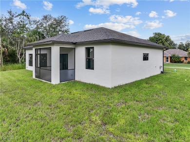 Back of property with a sunroom, stucco siding, a yard, and a shingled roof