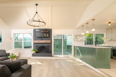 Living area featuring light wood-style flooring, a fireplace, a chandelier, vaulted ceiling, and wood ceiling