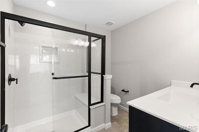 Bathroom with tile patterned floors, a shower with door, vanity, and toilet