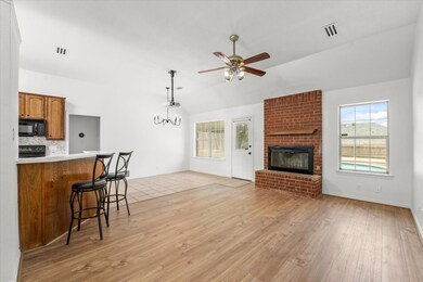 Kitchen with light hardwood / wood-style floors, a fireplace, lofted ceiling, and tasteful backsplash