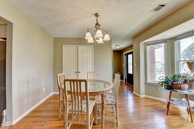 Dining space with light wood-type flooring, a chandelier, and a textured ceiling