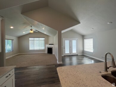 Unfurnished living room featuring lofted ceiling, plenty of natural light, dark wood-style flooring, recessed lighting, and a fireplace with flush hearth