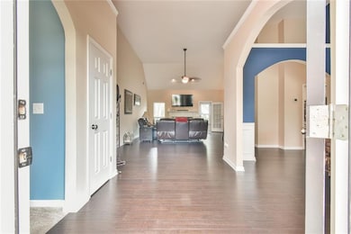 Foyer with dark wood-style floors, baseboards, arc