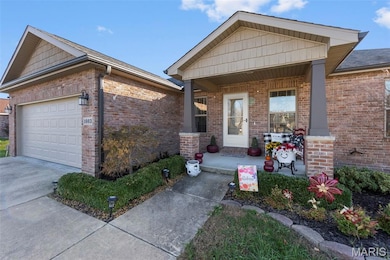 View of front of home featuring a porch, brick siding, an attached garage, and concrete driveway