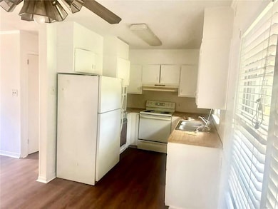 Kitchen featuring white cabinetry, sink, ceiling fan, dark wood-type flooring, and white appliances