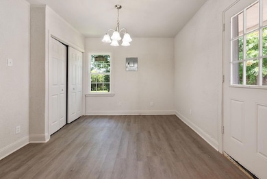 Unfurnished dining area with healthy amount of natural light, a chandelier, wood finished floors, and electric panel