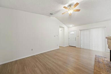 Unfurnished living room with vaulted ceiling, light wood finished floors, a textured ceiling, and a ceiling fan