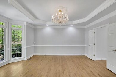 Unfurnished room featuring an inviting chandelier, a tray ceiling, ornamental molding, light wood-style floors, and baseboards