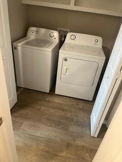 Washroom with dark wood-style floors and washing machine and dryer